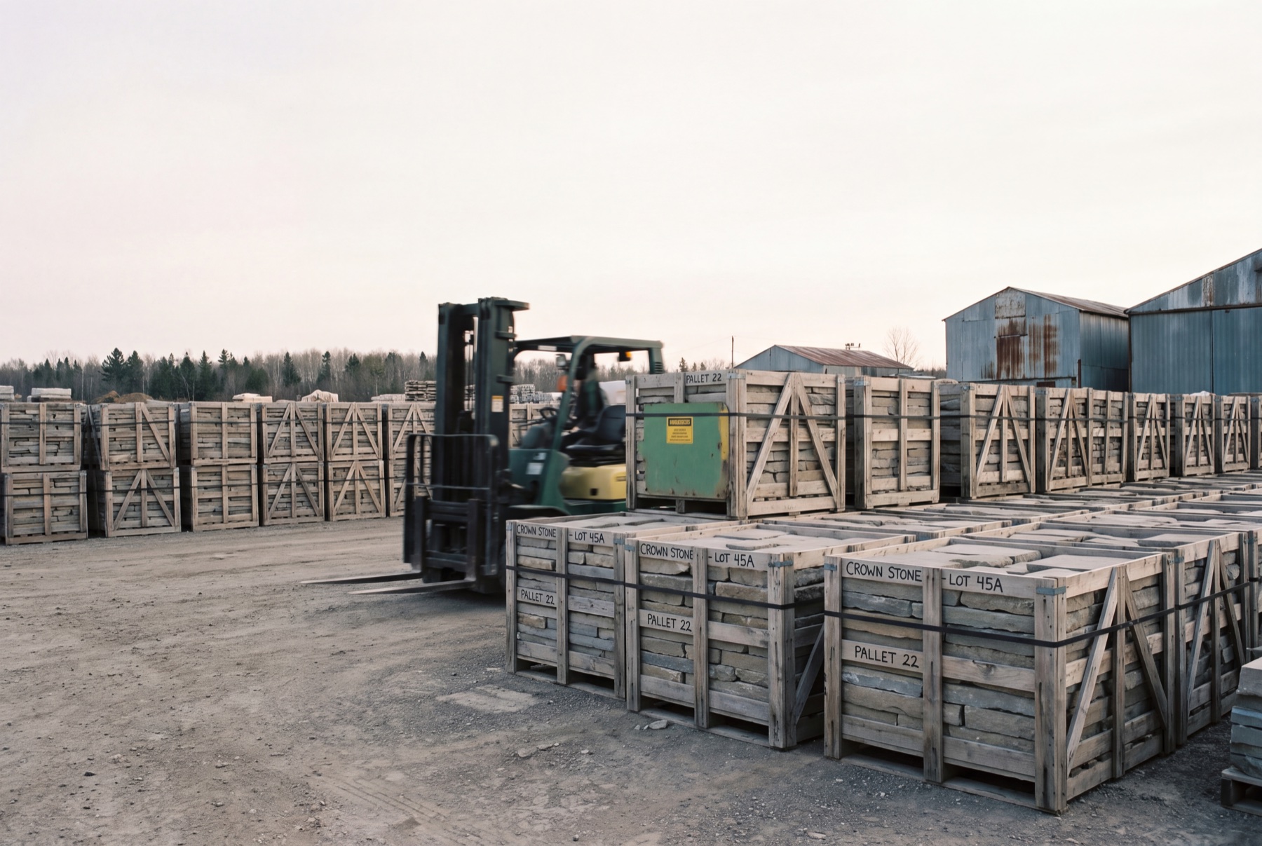 Neat rows of banded stone paver crates staged in a Canadian laydown yard.