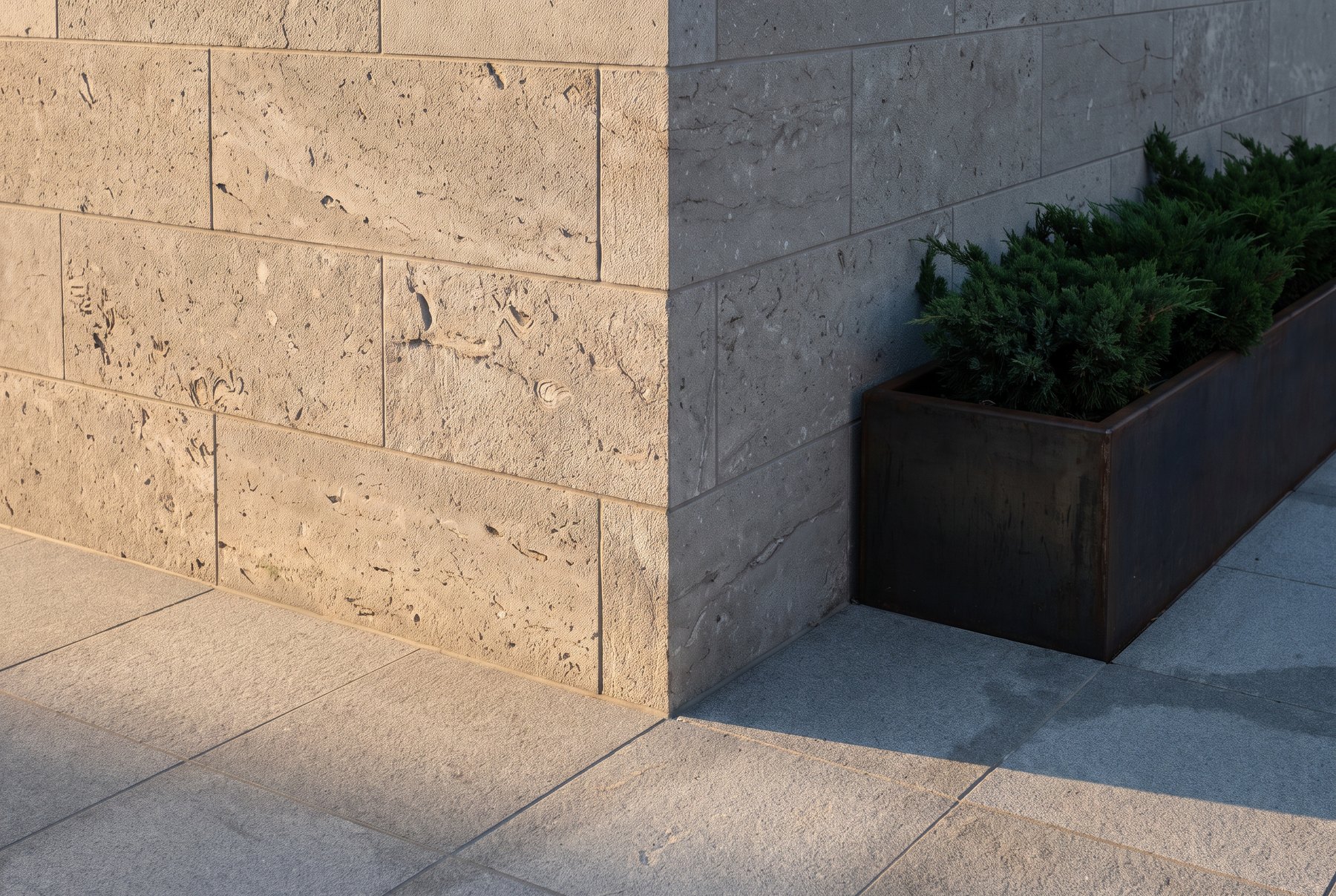 A limestone veneer wall above Fine Grey granite paving at a completed commercial courtyard.